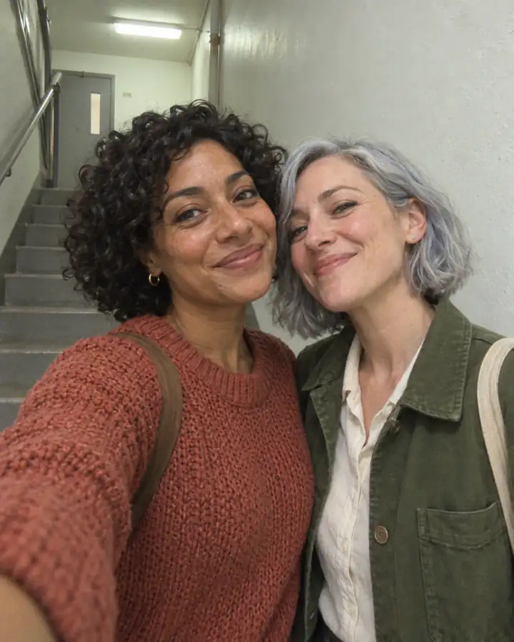 Una selfie casual tomada con un teléfono en unas escaleras de dos mujeres adultas.